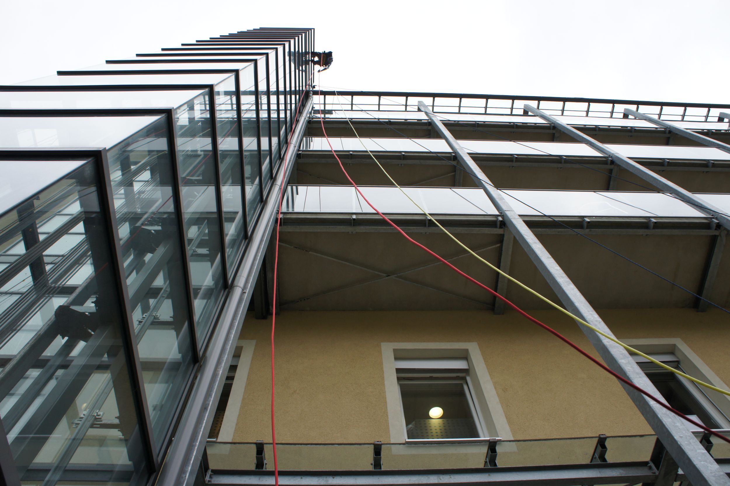 Industriekletterer reinigt die Fassade eines modernen Gebäudes mit Glasfront.